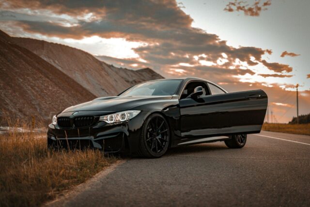 Why Replacing a Car Part Shouldn't Mean Replacing the Car Black BMW coupe parked at the roadside with its door open at sunset