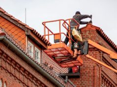 How to Choose a Roofer in Harrogate: What to Ask Before You Hire Roofer on a cherry picker repairing the tiled roof of a red brick building