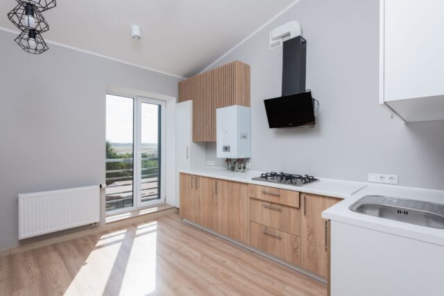 the-landlord-safety-checklist-what-actually-has-to-be-tested-and-how-o Empty rental flat kitchen with a wall-mounted gas boiler, gas hob and radiator