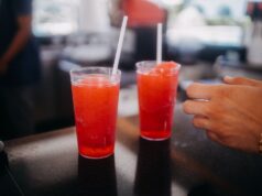 Two red slushy drinks with straws on a bar counter